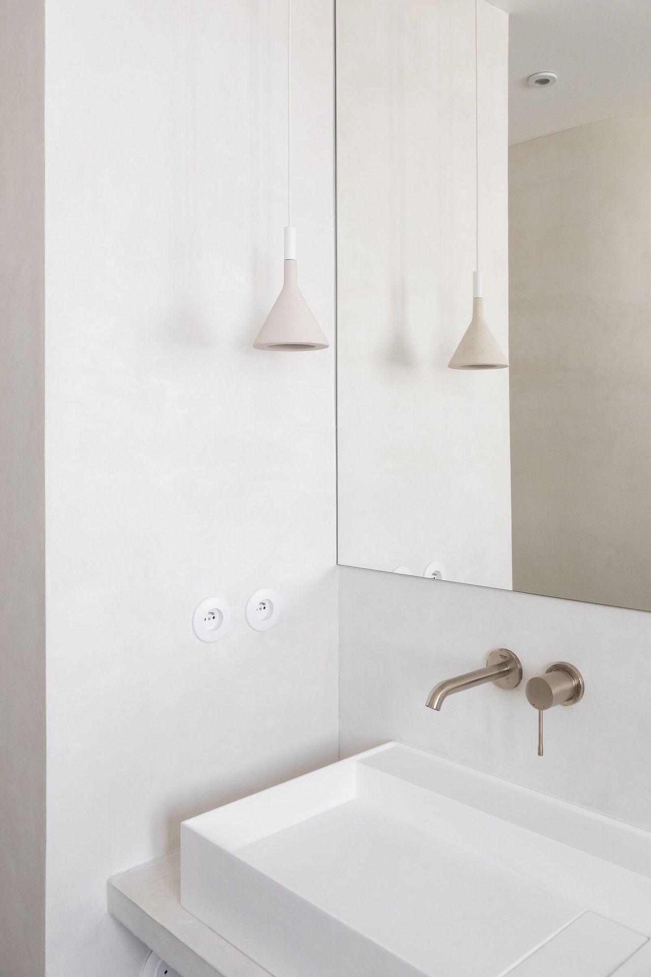 A Hatysa washbasin in Corian made from Riluxa in a white bathroom designed by Alak Studio